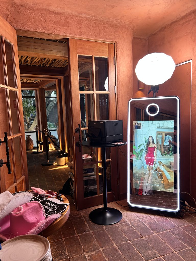 Mirror photobooth setup with lighting, printer and prop table. Customised touch to start screen for the booth.