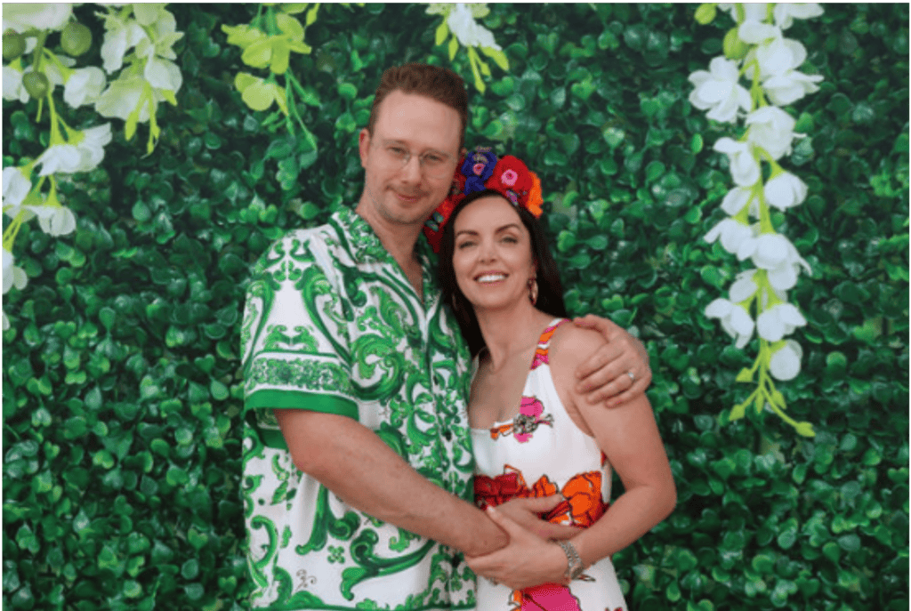 Couple posing in floral backdrop.