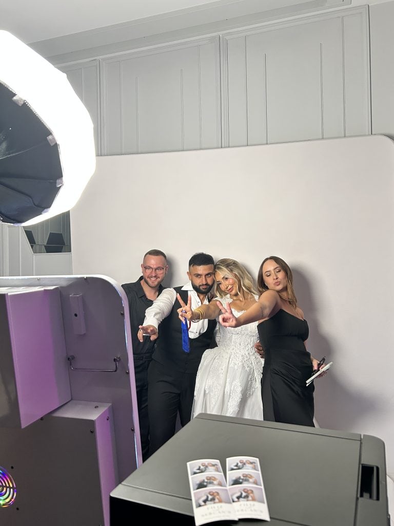 Group of four posing for a photo booth photo at a wedding.