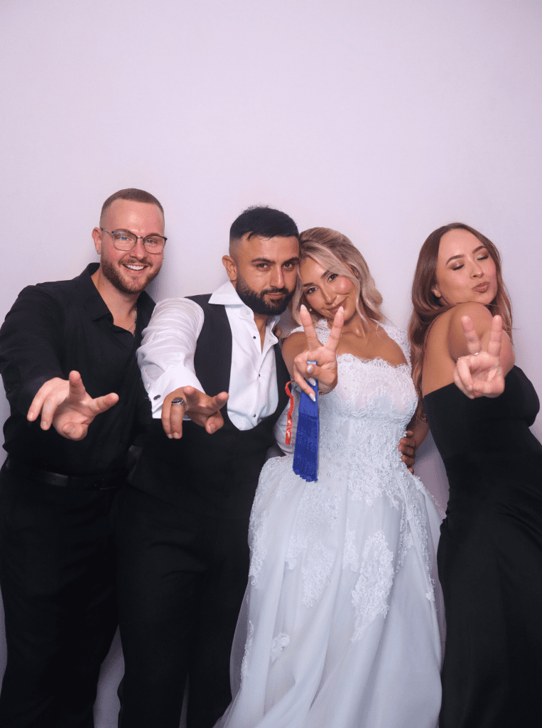Group of 4 holding 2 fingers in front of the mirror photobooth.