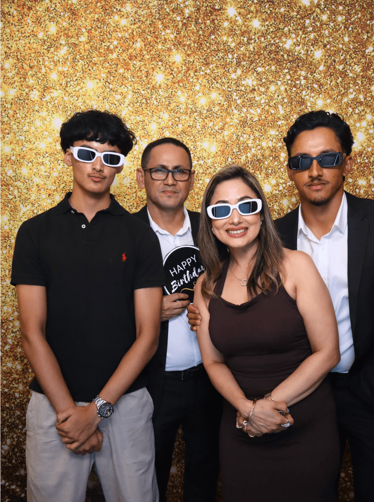 A 18 birthday event with a family of 4 people posing in front of the photo booth wearing glasses and formal outfits.